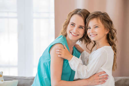 Happy mother and teenage daughter hug each other at home.の写真素材