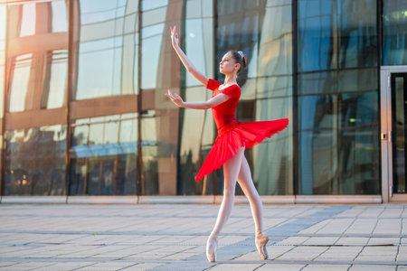 a young ballerina in a bright red tutu is dancing against the backdrop of a cityscapeの写真素材