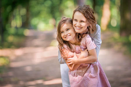 Mother and daughter are hugging in the park. Happy family concept. Beauty nature scene with family outdoor lifestyle. Happy family resting together. Happiness and harmony in family life.の写真素材