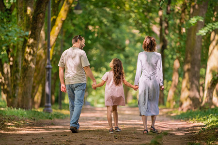 Portrait of a happy traditional family on a walk in a summer park, view from the back without a faceの写真素材