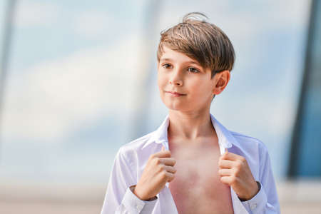 Portrait of a happy boy in an unbuttoned shirt on a summer sky backgroundの写真素材