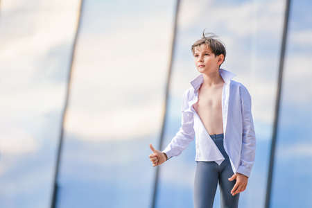 Portrait of happy boy dancer in unbuttoned shirt on sky background showing hand gesture excellent.の写真素材