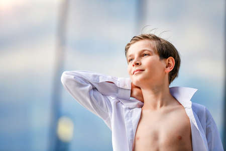 Portrait of a happy boy in an unbuttoned shirt on a summer sky backgroundの写真素材