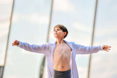 portrait of a ballet boy exercising against a background of sky reflection in a glass wallの写真素材