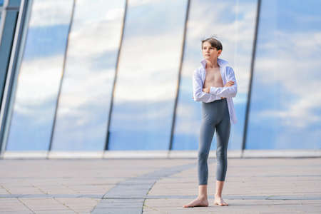 portrait of a ballet boy exercising against a background of sky reflection in a glass wallの写真素材