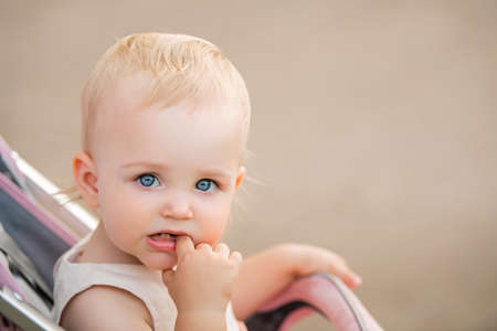 Portrait of a blue-eyed baby sucking a finger in her mouth, two first teeth are visible.の写真素材