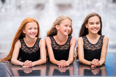 Portrait of three teenage girls with loose hair, blonde, redhead and brunette Summer on the street. Vloses develop in the wind.の写真素材