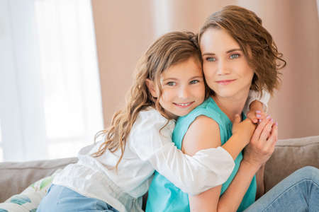 Happy mother and teenage daughter hug each other at home.の写真素材