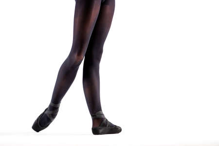 Ballerina legs in a black pointe shoes and leotards standing isolated on white backgroundの写真素材