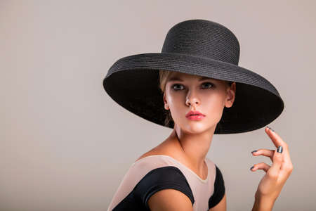 Romantic portrait of a beautiful young girl on a light background in an elegant hatの写真素材