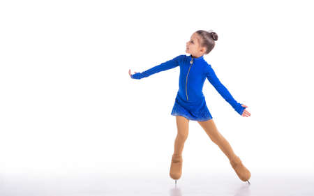 Little young figure skater posing in blue training dress on ice on white backgroundの写真素材