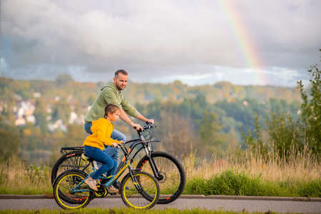 Happy father and daughter take a bike ride in nature in autumn.の写真素材