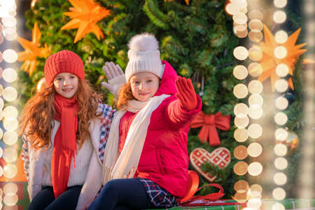 Children of the red-haired sisters walk together at a festively decorated Christmas market in the city.の写真素材