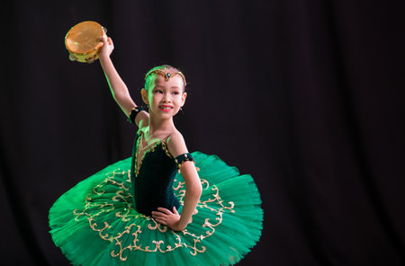 little girl ballerina is dancing on stage in tutu on pointe shoes with tambourine, classic variation of Esmeralda.の写真素材