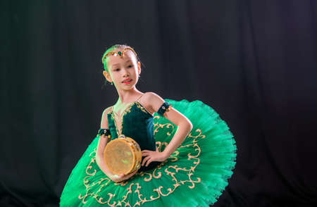 little girl ballerina is dancing on stage in tutu on pointe shoes with tambourine, classic variation of Esmeralda.の写真素材