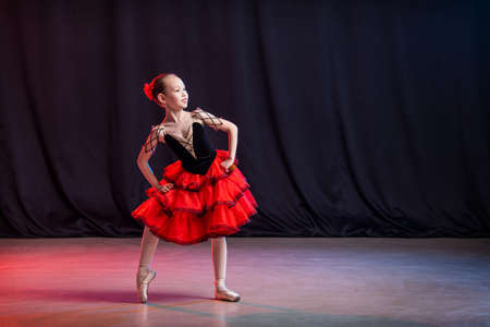little girl ballerina is dancing on stage in tutu on pointe shoes with castanedas, the classic variation of Kitri.の写真素材
