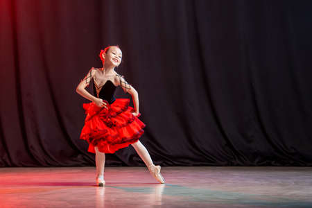 little girl ballerina is dancing on stage in tutu on pointe shoes with castanedas, the classic variation of Kitri.の写真素材