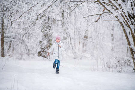 little girl child running in winter in a snowy parkの写真素材