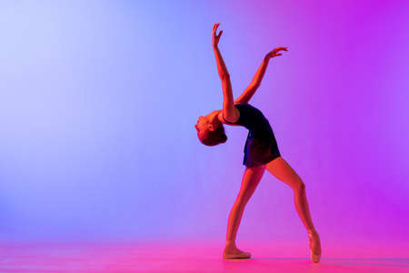 Beautiful young girl ballerina in pointe shoes and a pink leotard silhouette on a bright blue background.の写真素材
