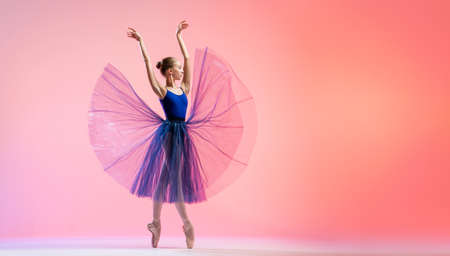 Beautiful young girl ballerina in pointe shoes and swimsuit silhouette on bright red background.の写真素材