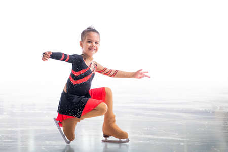 Little skater posing in red and black dress on ice isolated on white backgroundの写真素材