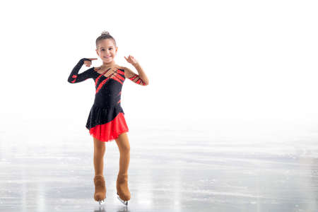 Little skater posing in red and black dress on ice isolated on white backgroundの写真素材