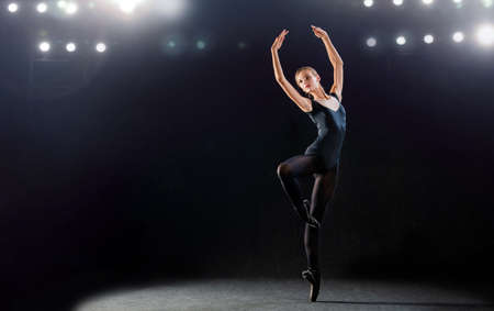 ballerina in a tight-fitting suit is dancing on a black background on pointe shoes, the silhouette is illuminated by sources of color.の写真素材