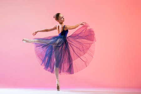 Beautiful young girl ballerina in pointe shoes and swimsuit silhouette on bright red background.の写真素材