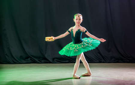 little girl ballerina is dancing on stage in tutu on pointe shoes with tambourine, classic variation of Esmeralda.の写真素材
