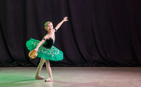 little girl ballerina is dancing on stage in tutu on pointe shoes with tambourine, classic variation of Esmeralda.の写真素材