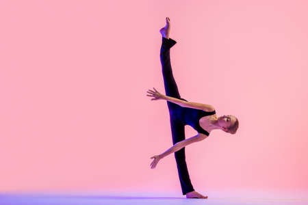 Young teenager dancer dancing on red studio background. Ballet, dance, art, modernity, choreography conceptの写真素材