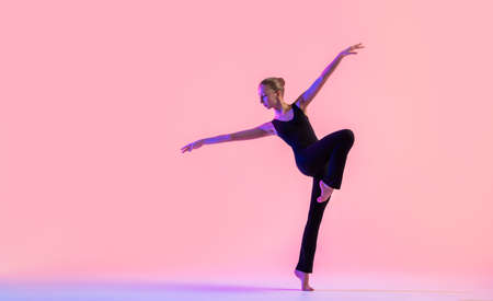 Young teenager dancer dancing on red studio background. Ballet, dance, art, modernity, choreography conceptの写真素材