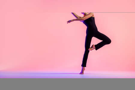 Young teenager dancer dancing on red studio background. Ballet, dance, art, modernity, choreography conceptの写真素材