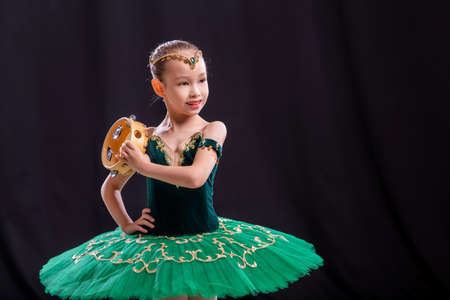 little girl ballerina is dancing on stage in tutu on pointe shoes with tambourine, classic variation of Esmeralda.の写真素材