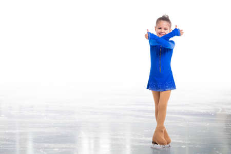 Little young skater posing in blue training dress on ice showing success gesture isolated on white backgroundの写真素材