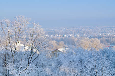 Rural winter hilly landscape. roofs of the houses are covered with snow on frosty sunny day.