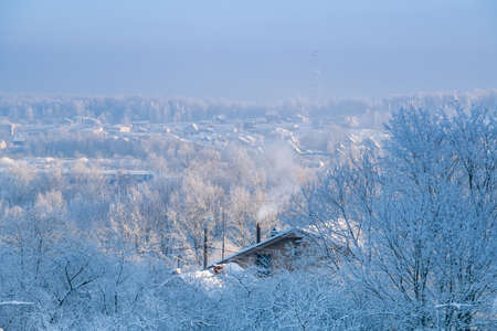 Rural winter hilly landscape. roofs of the houses are covered with snow on frosty sunny day.の写真素材