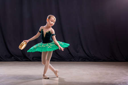little girl ballerina is dancing on stage in tutu on pointe shoes with tambourine, classic variation of Esmeralda.の写真素材
