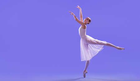 elegant ballerina in pointe shoes is dancing in a long flying white skirt on a lilac light backgroundの写真素材