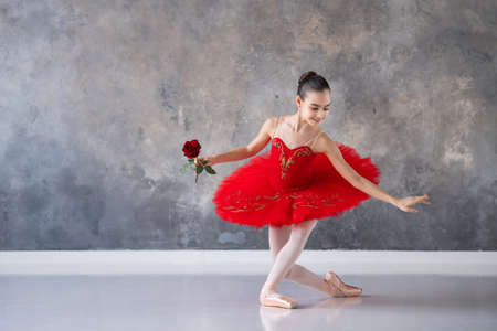 cute little girl dreams of becoming a professional ballerina. girl in bright red tutu on pointe shoes dances in hall. Vocational school student.の写真素材