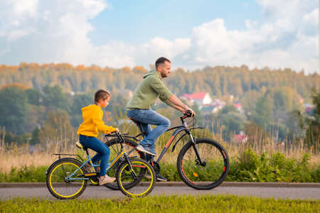 Happy father and daughter take a bike ride in nature in autumn.の写真素材