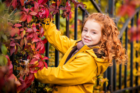 portrait of happy cheerful red-haired curly teenage girl in nature among the bright autumn forest.の写真素材