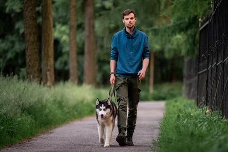 cute young man is walking along the road with his beloved Siberian Husky dog in nature.の写真素材