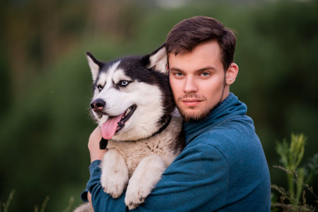 Portrait of handsome young man and his pet dog Siberian Husky in nature.の写真素材