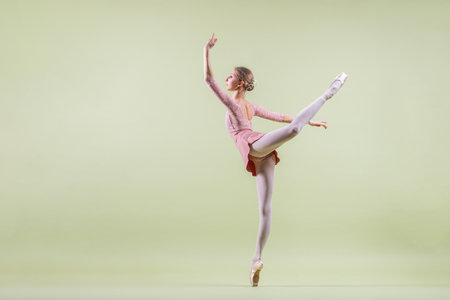 elegant young ballerina in pointe shoes dancing on a gentle green backgroundの写真素材