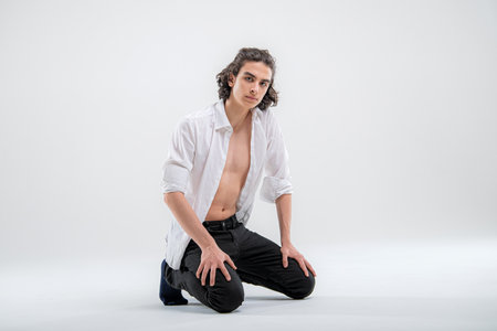 Full-length portrait of standing handsome young man model in white shirt and jeans on white background.の写真素材