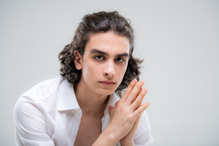 Portrait of a handsome young man with lush curly hair on white backgroundの写真素材