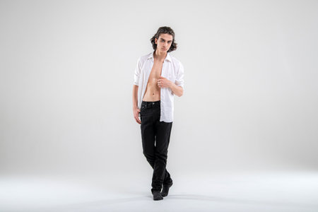 Full-length portrait of standing handsome young man model in white shirt and jeans on white background.の写真素材