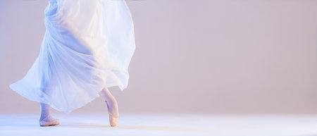 legs of a ballerina in pointe shoes stand under a developing flying skirt on a white backgroundの写真素材