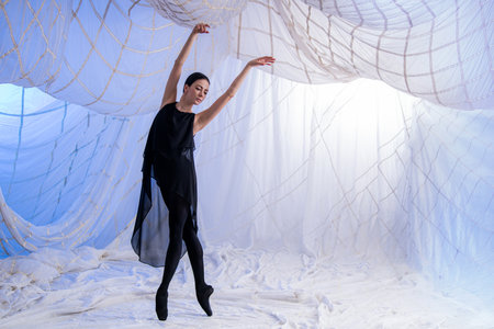 Ballerina dancer in a black suit dances on a blue background. The concept of freedom and grace as a...